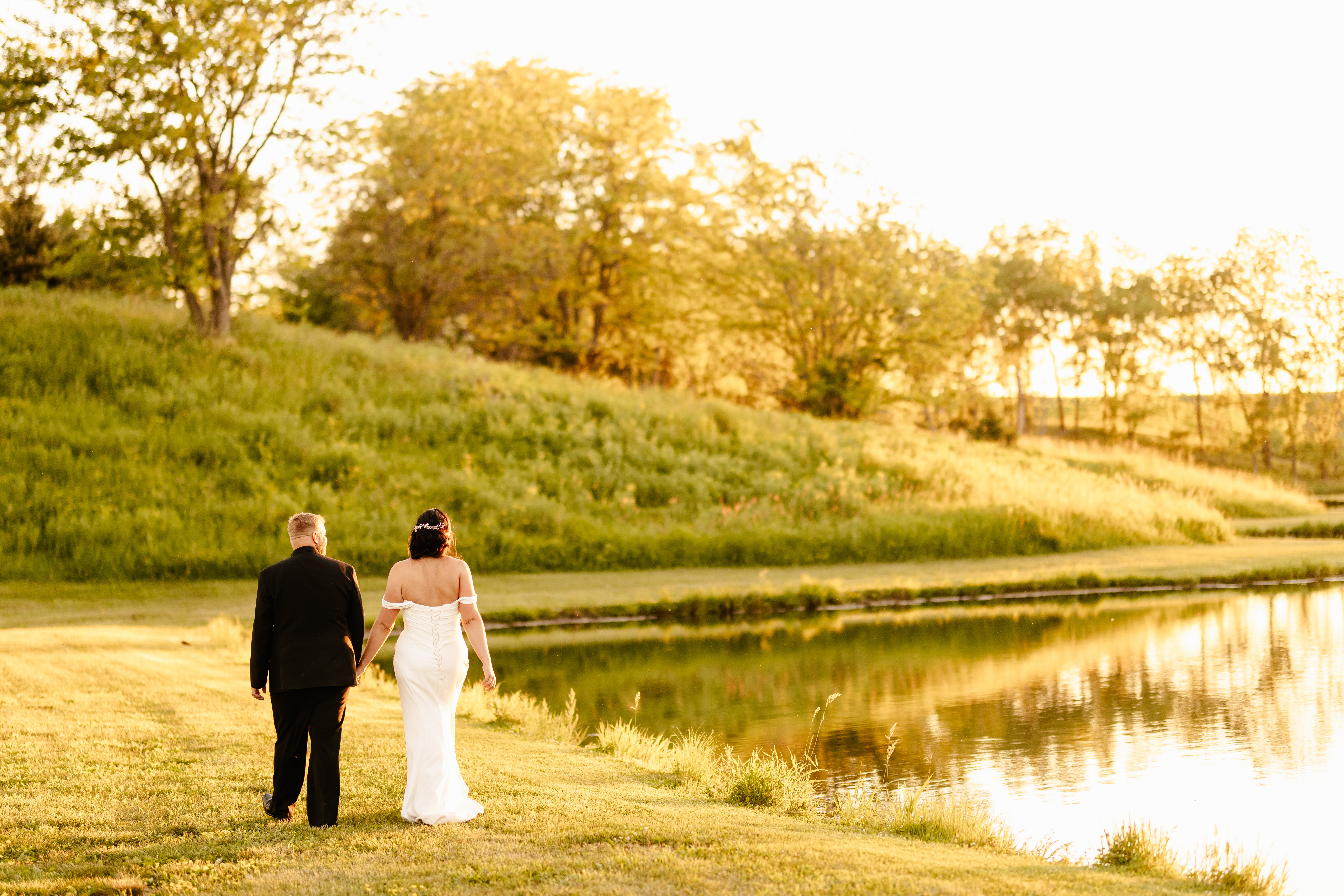 bride and groom walking by lake during sunset portraits